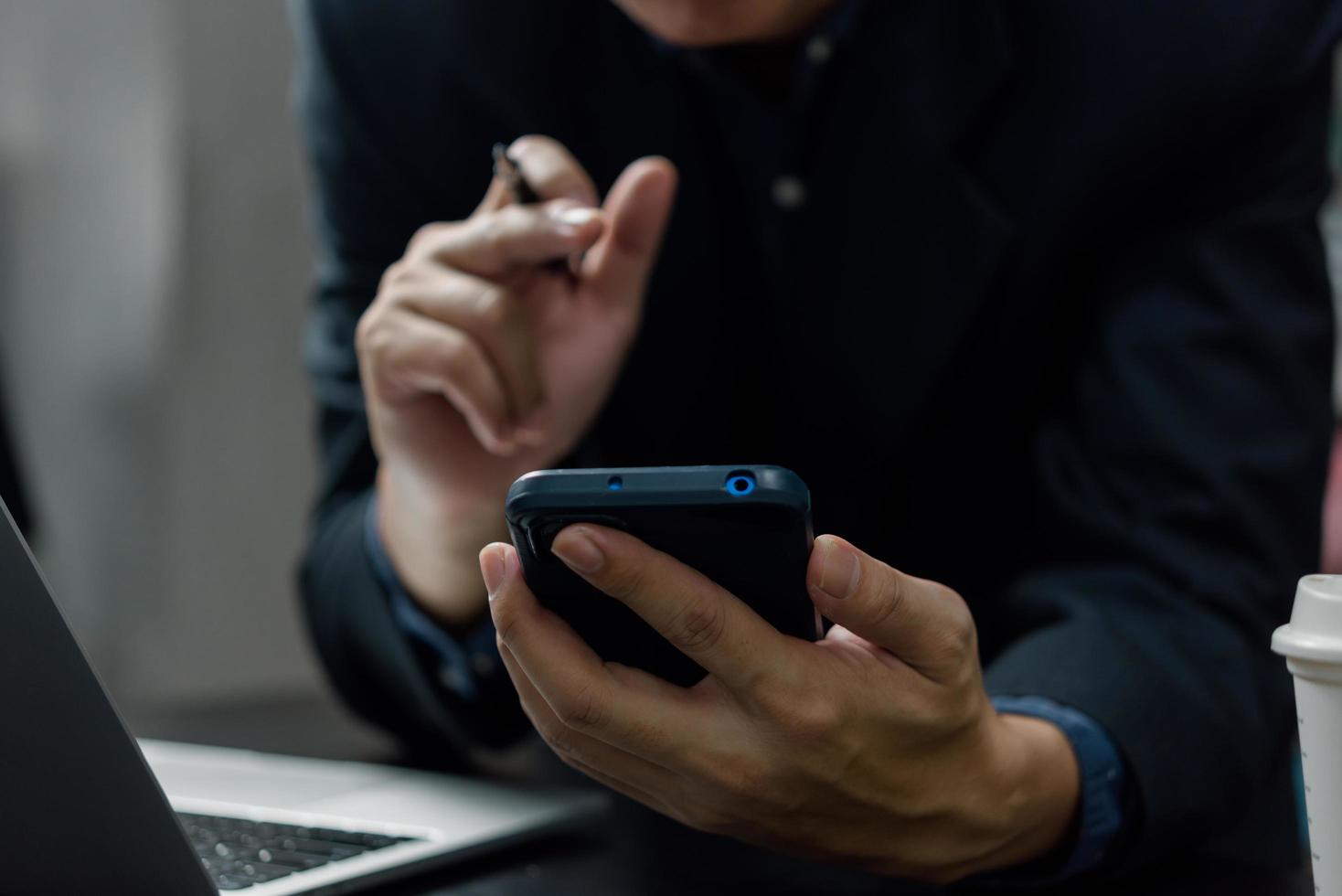 Man hand holding mobile smartphone digital technology network communications at desk. photo