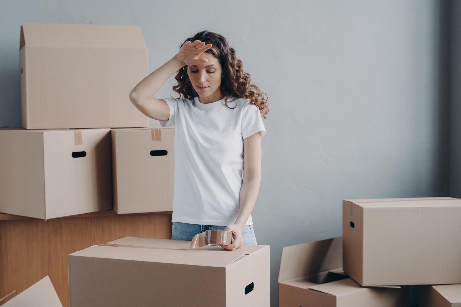 mujer cansada empacando cajas de cartón con cosas, preparándose para mudarse a un nuevo hogar. día de mudanza difícil foto