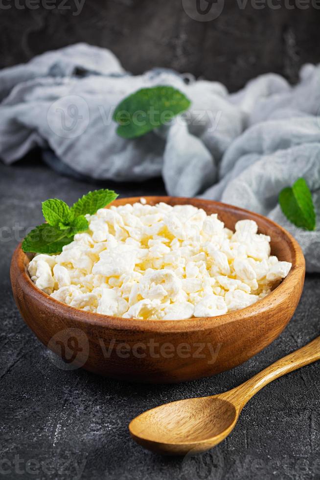 Bowl of cottage cheese on dark background. Fresh homemade cottage cheese photo