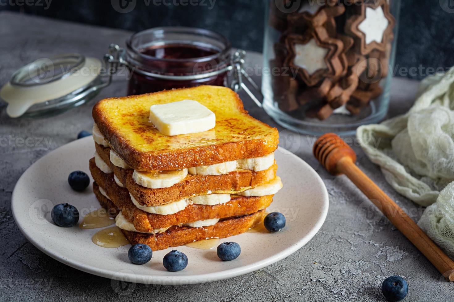 torrija con plátano, arándanos, miel y mermelada de fresa. delicioso desayuno matutino o brunch con tostadas y galletas foto