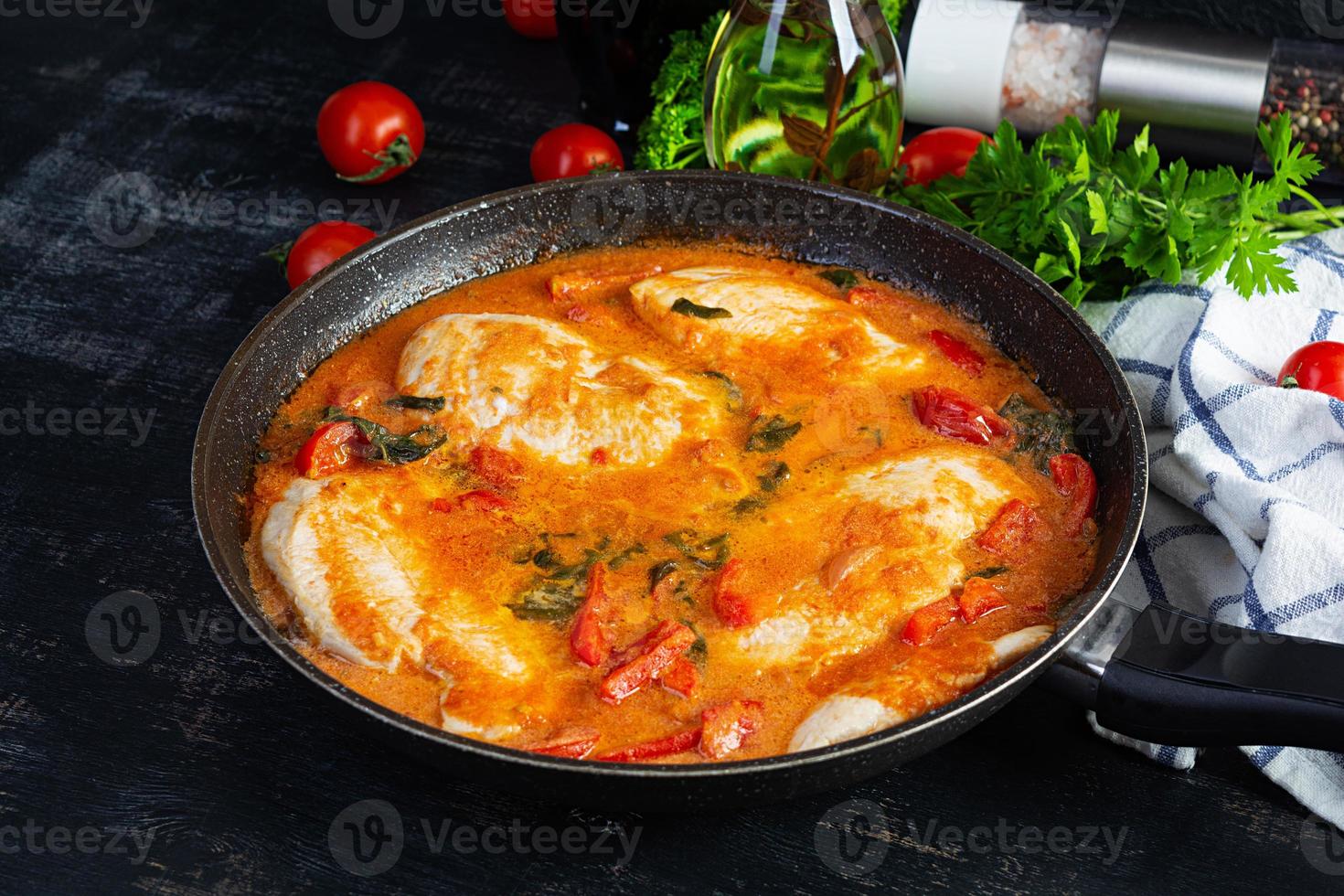 Stew chicken breast with tomato, pepper and spinach in pan photo