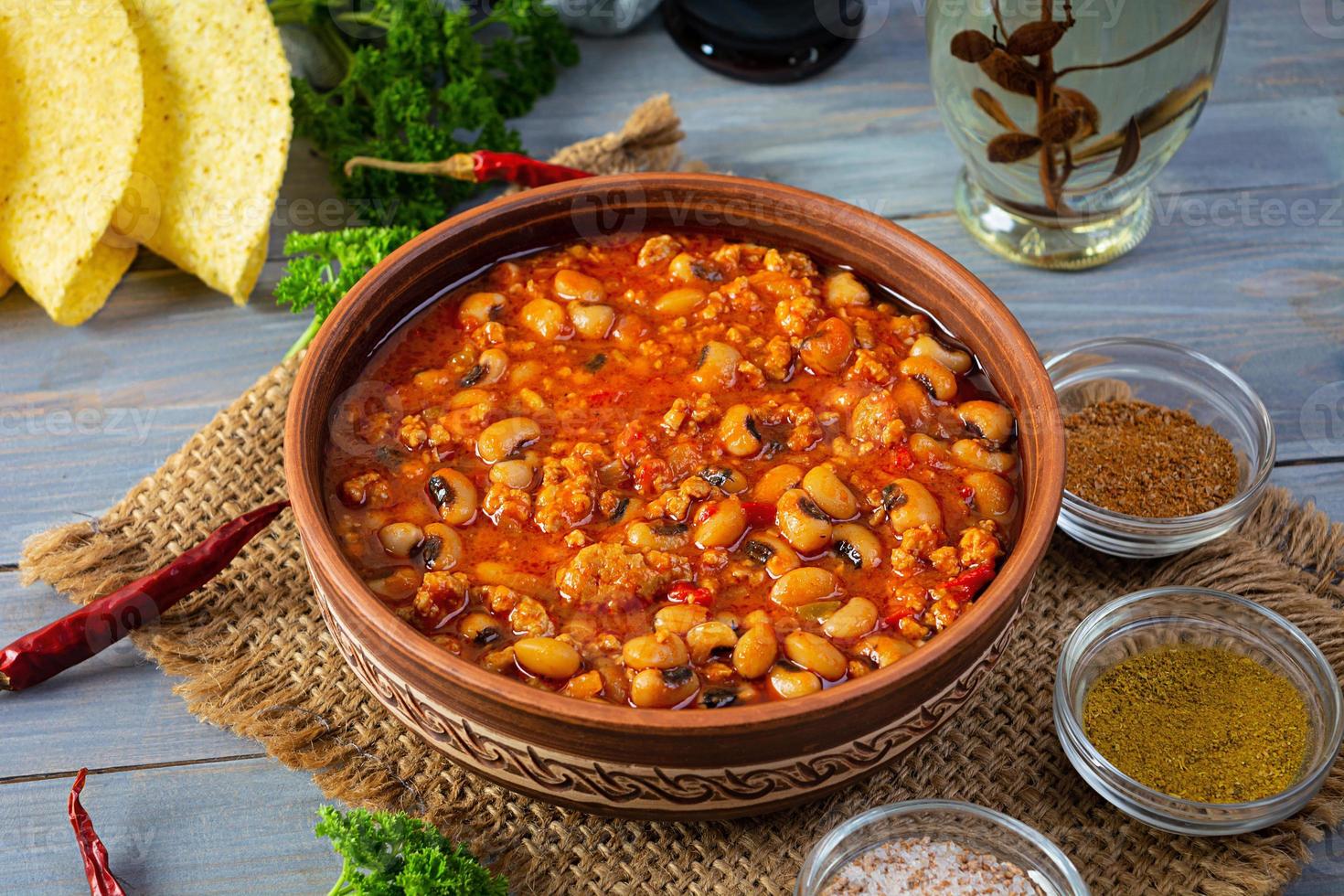 Chili con carne in a bowl on wooden background. Mexican cuisine photo