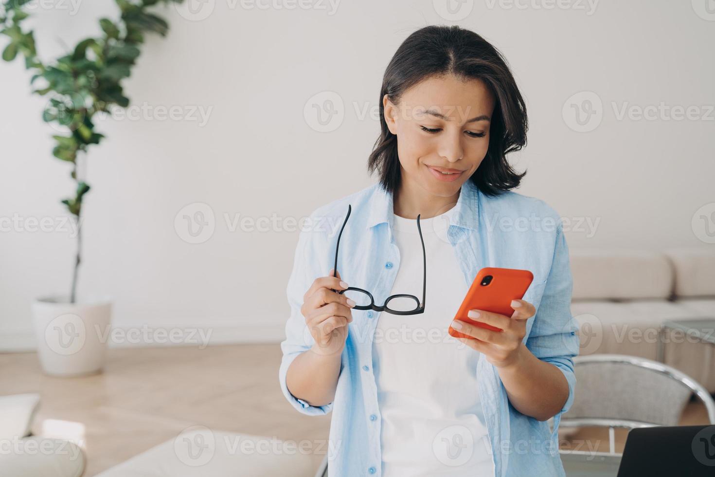 Businesswoman using phone apps in office, reading message with good news, making mobile phone call photo