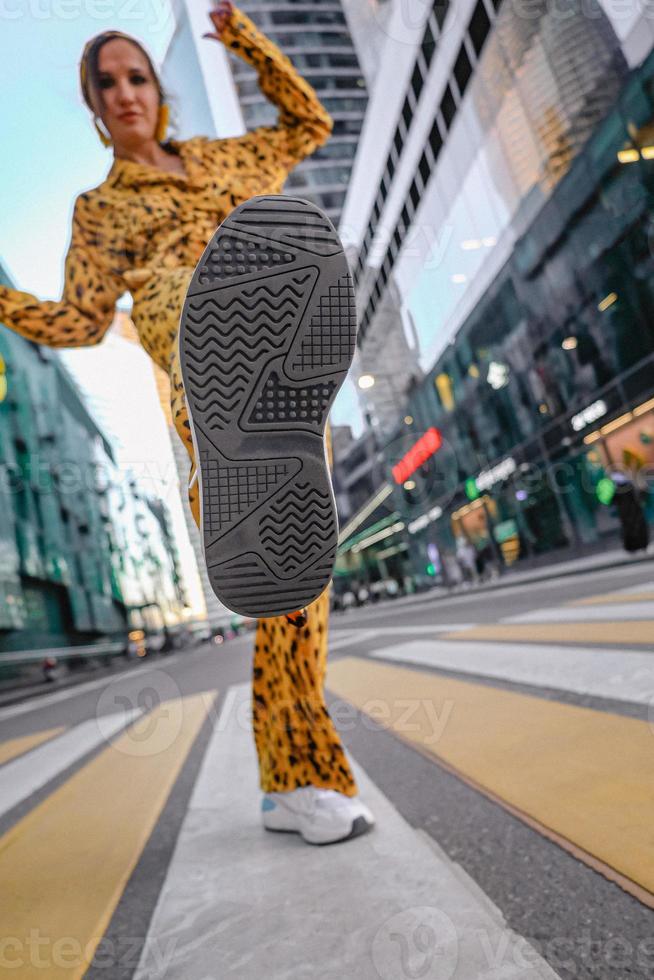 A beautiful shot of a woman in yellow, lifting her heel, and the Moscow City in the background photo