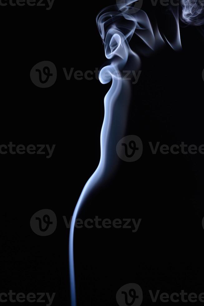 un disparo vertical de humo de tabaco azul sobre un fondo negro foto