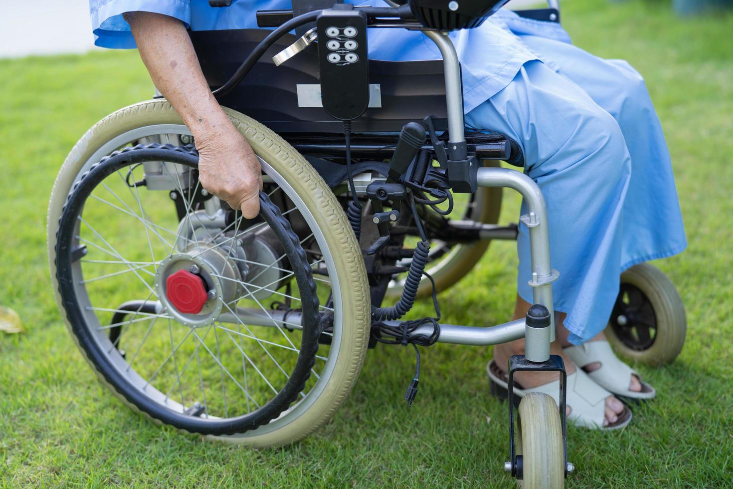Paciente asiático mayor o anciano en silla de ruedas eléctrica con control remoto en la sala del hospital de enfermería, concepto médico fuerte y saludable foto