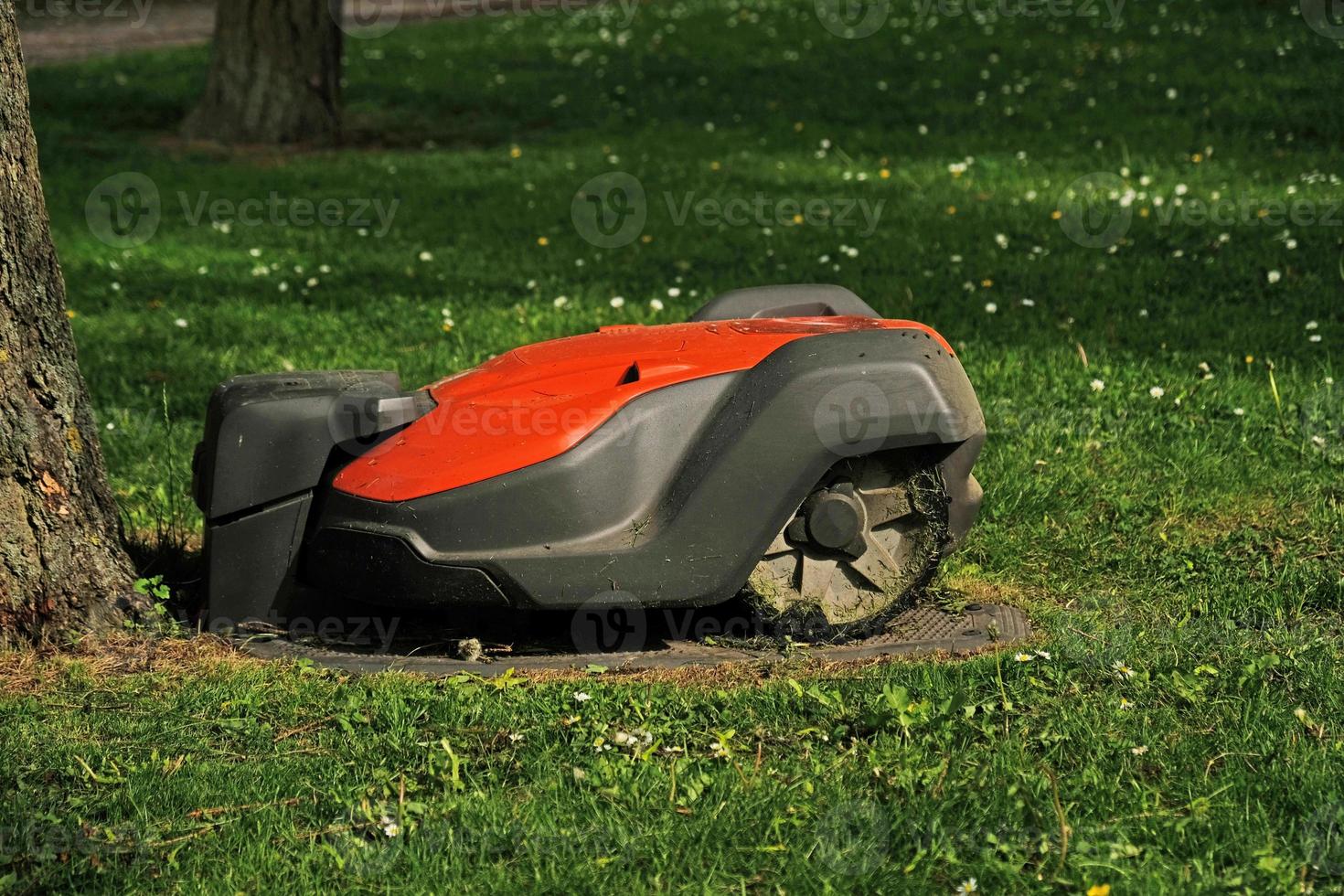 Robotic Lawn Mower on green grass background.Automatic robot lawnmower in modern garden.Green grass trimming with lawn mower. Close-up view of the lawn mower dirty blade after mowing the lawn. photo