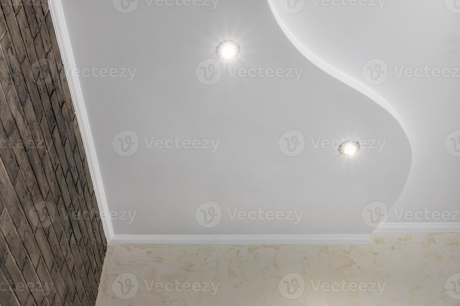 Detail of corner ceiling with intricate crown molding. Suspended ceiling and drywall construction in empty room in apartment or house. Stretch ceiling white and complex shape. photo