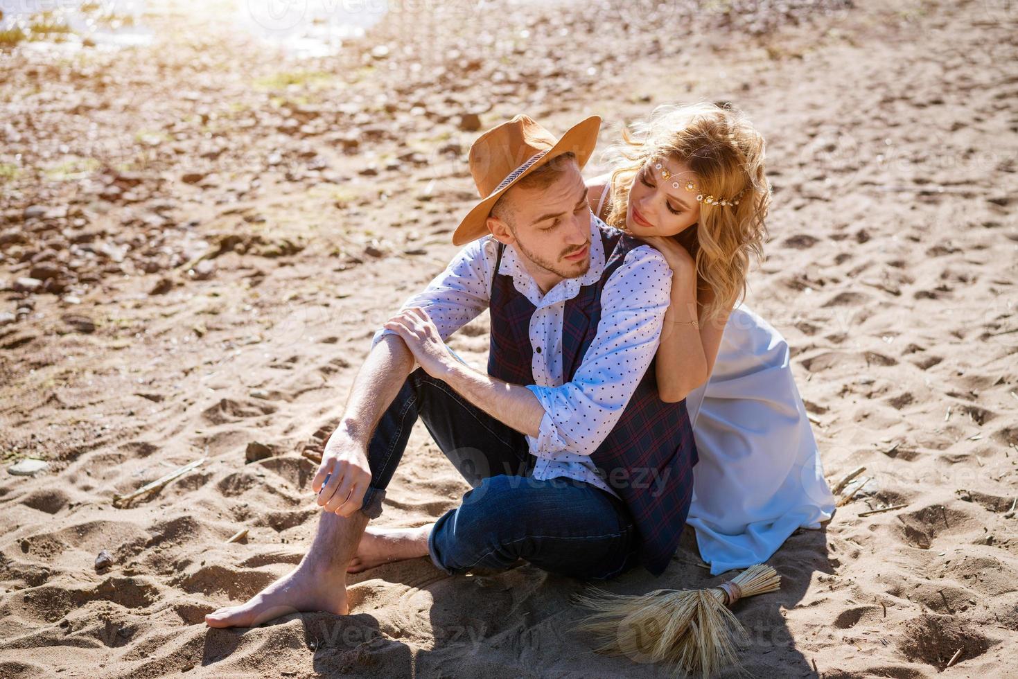 young couple is sitting on sand in an embrace on the background of the