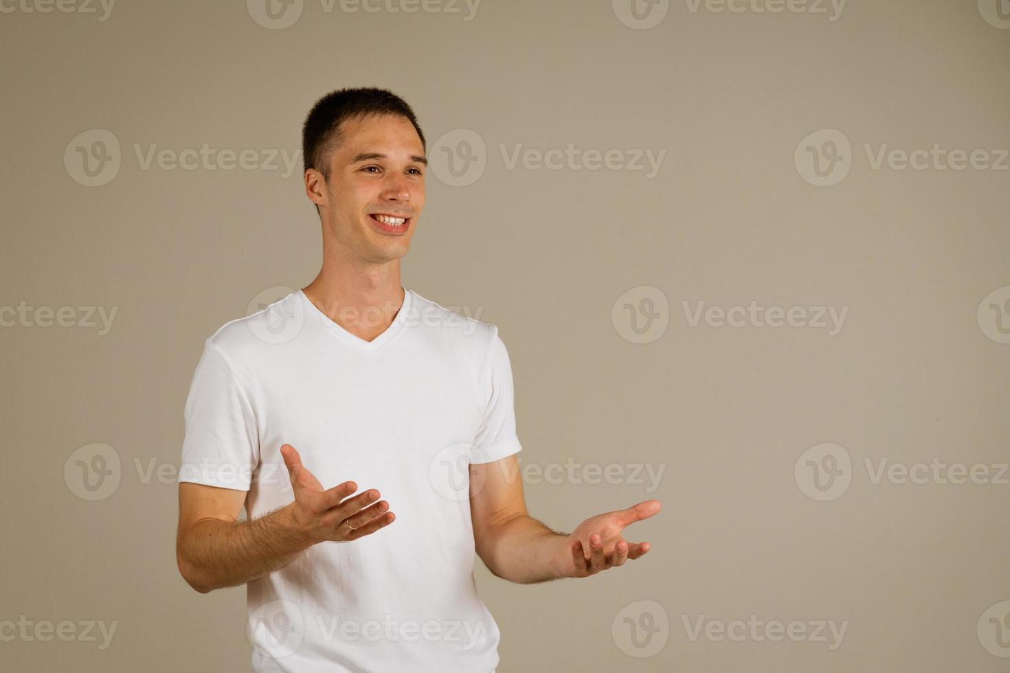 man in a white T-shirt gestures against the background photo