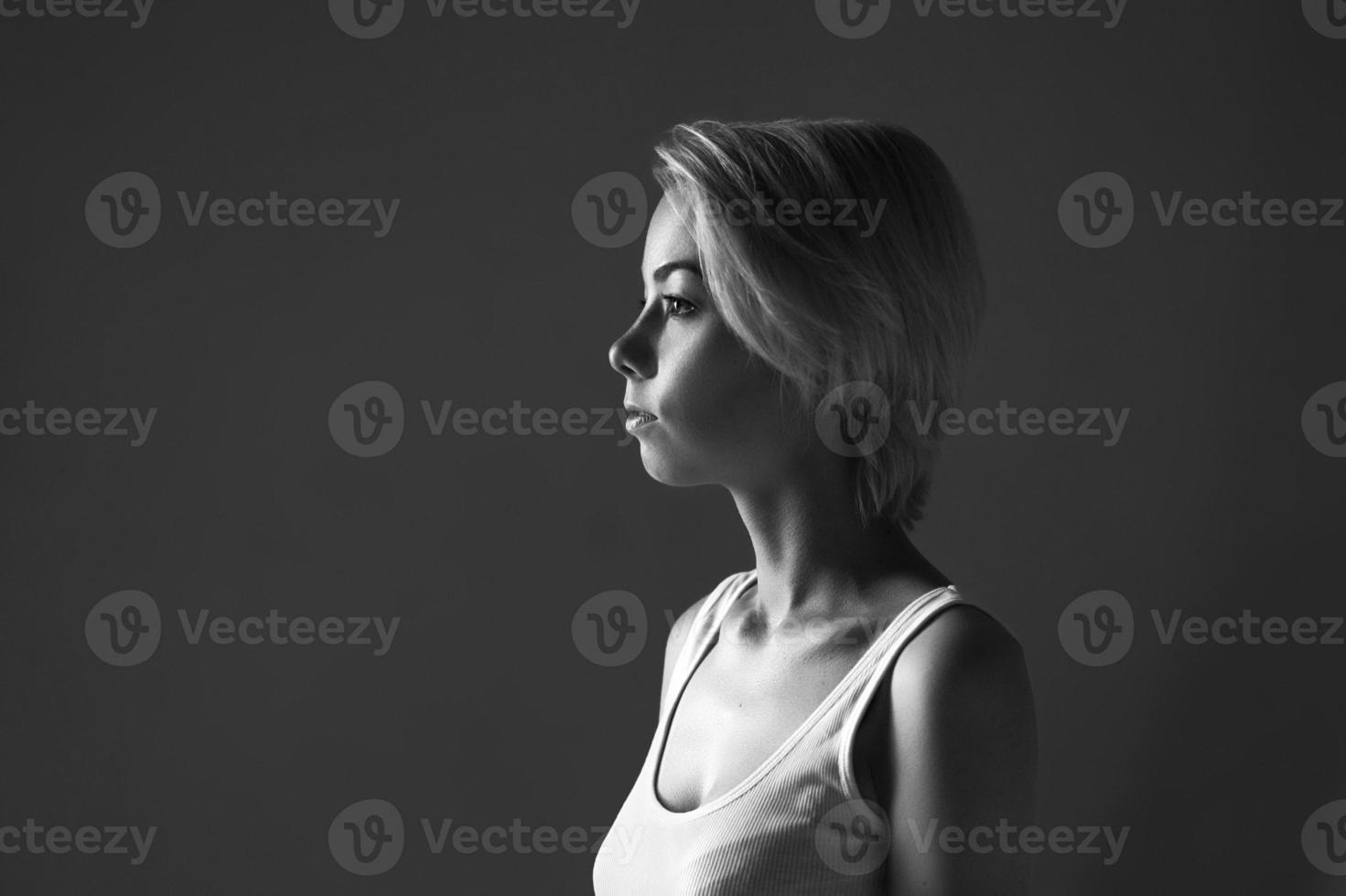 retrato de una mujer joven en un fondo oscuro mirando hacia otro lado, foto en blanco y negro