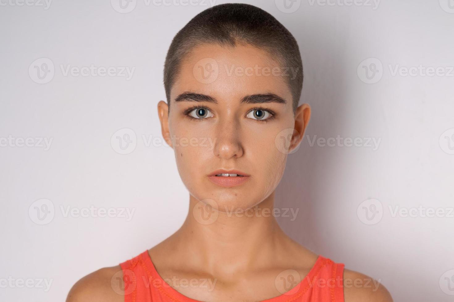 Caucasian young woman with shaved head. Young woman looking into the camera photo