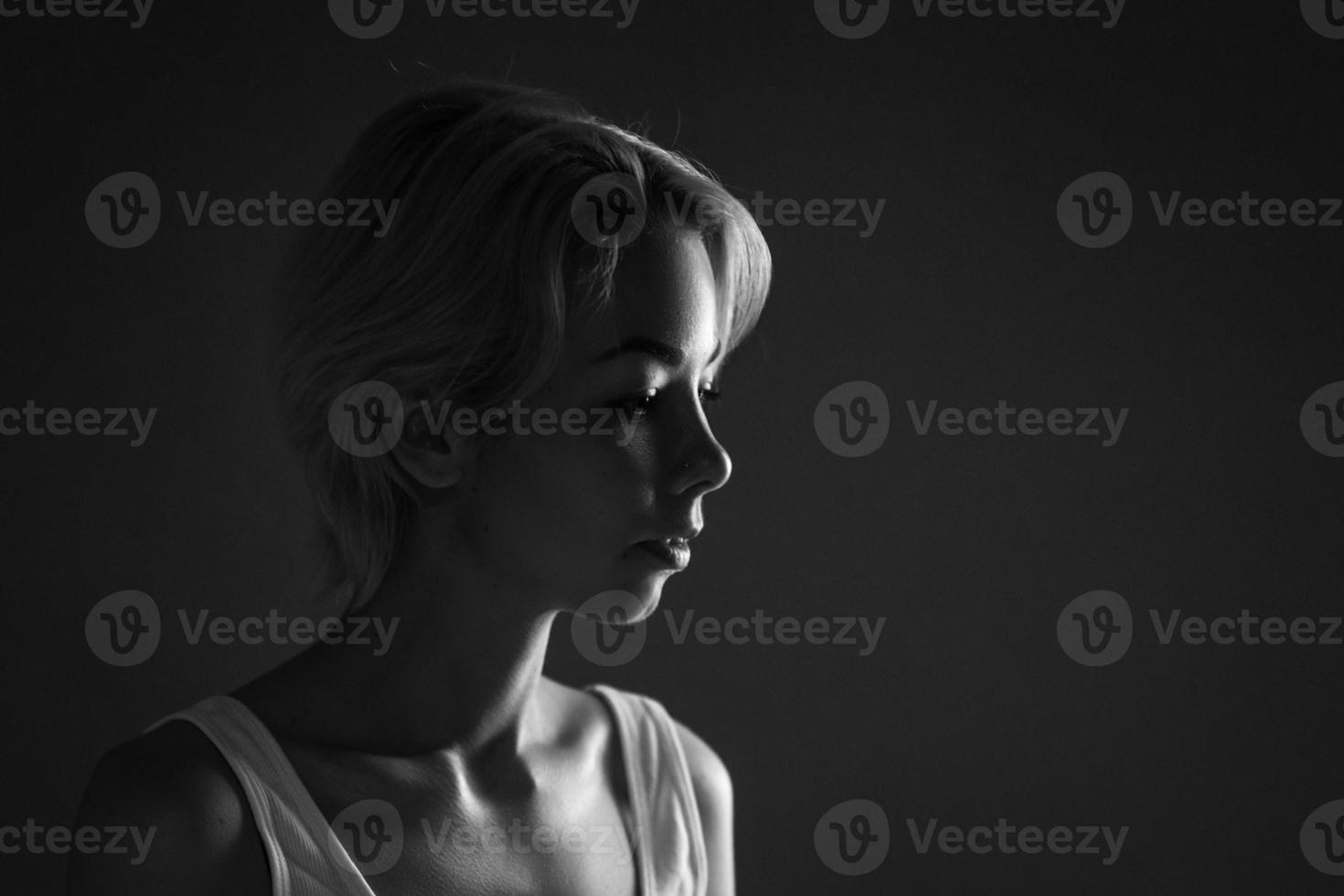 Female portrait close-up looks away, black and white photo dark