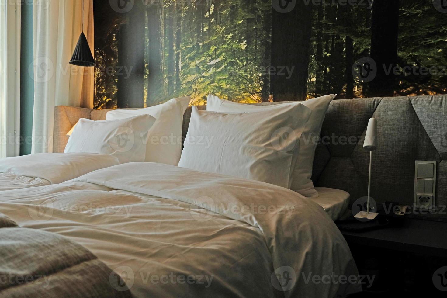 A fragment of a bedroom with a modern cozy interior design of a house or hotel. Soft pillow and blanket, stylish comfortable furniture. photo