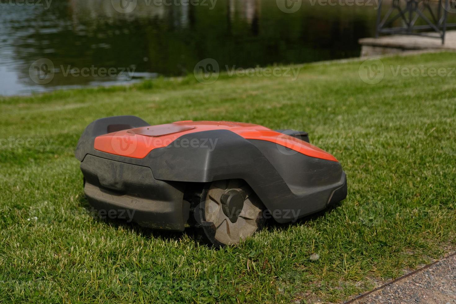 Robotic Lawn Mower on green grass background.Automatic robot lawnmower in modern garden.Green grass trimming with lawn mower. Close-up view of the lawn mower dirty blade after mowing the lawn. photo