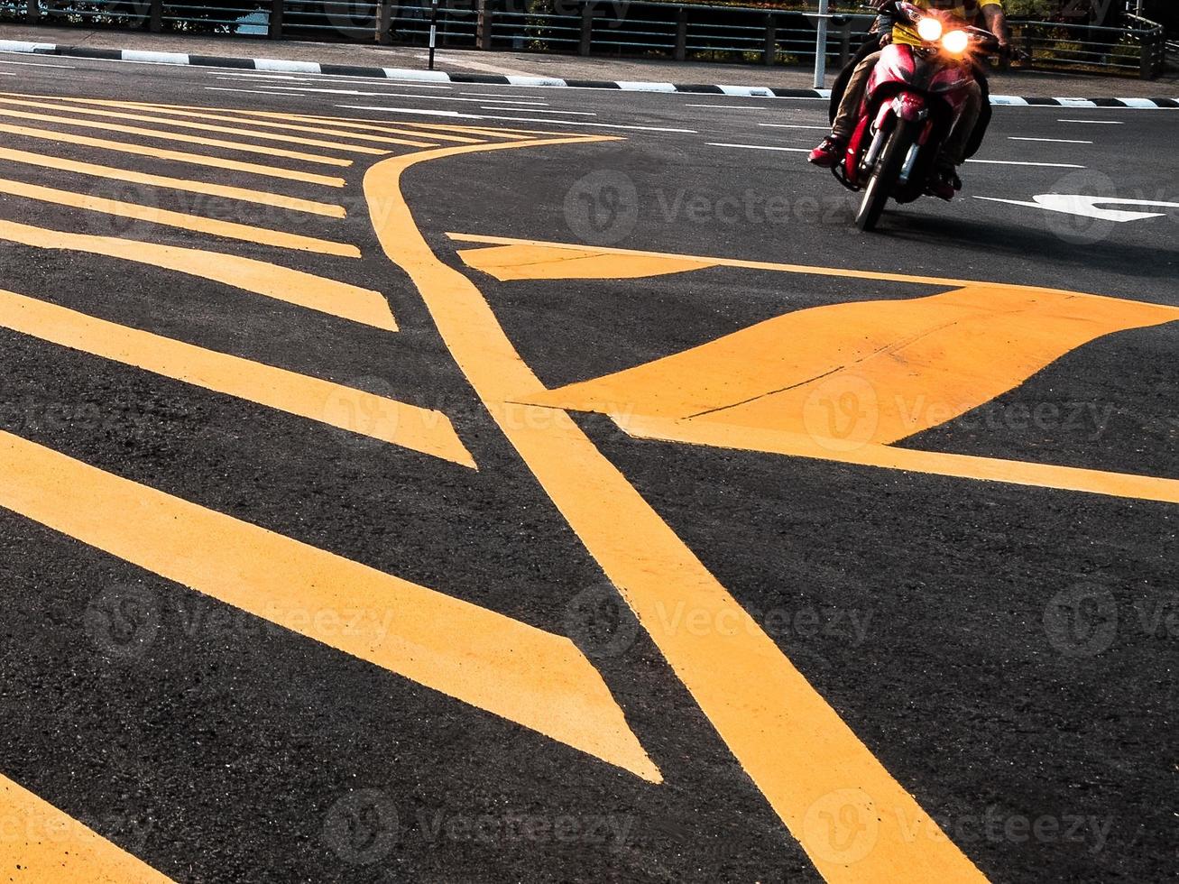 Low angle view of a motor cyclist driving past the yellow road markings photo