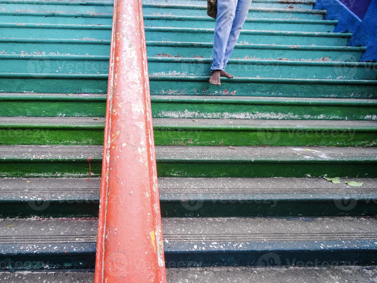 primer plano de un hombre descalzo descendiendo por unos coloridos escalones en las cuevas de batu, malasia foto