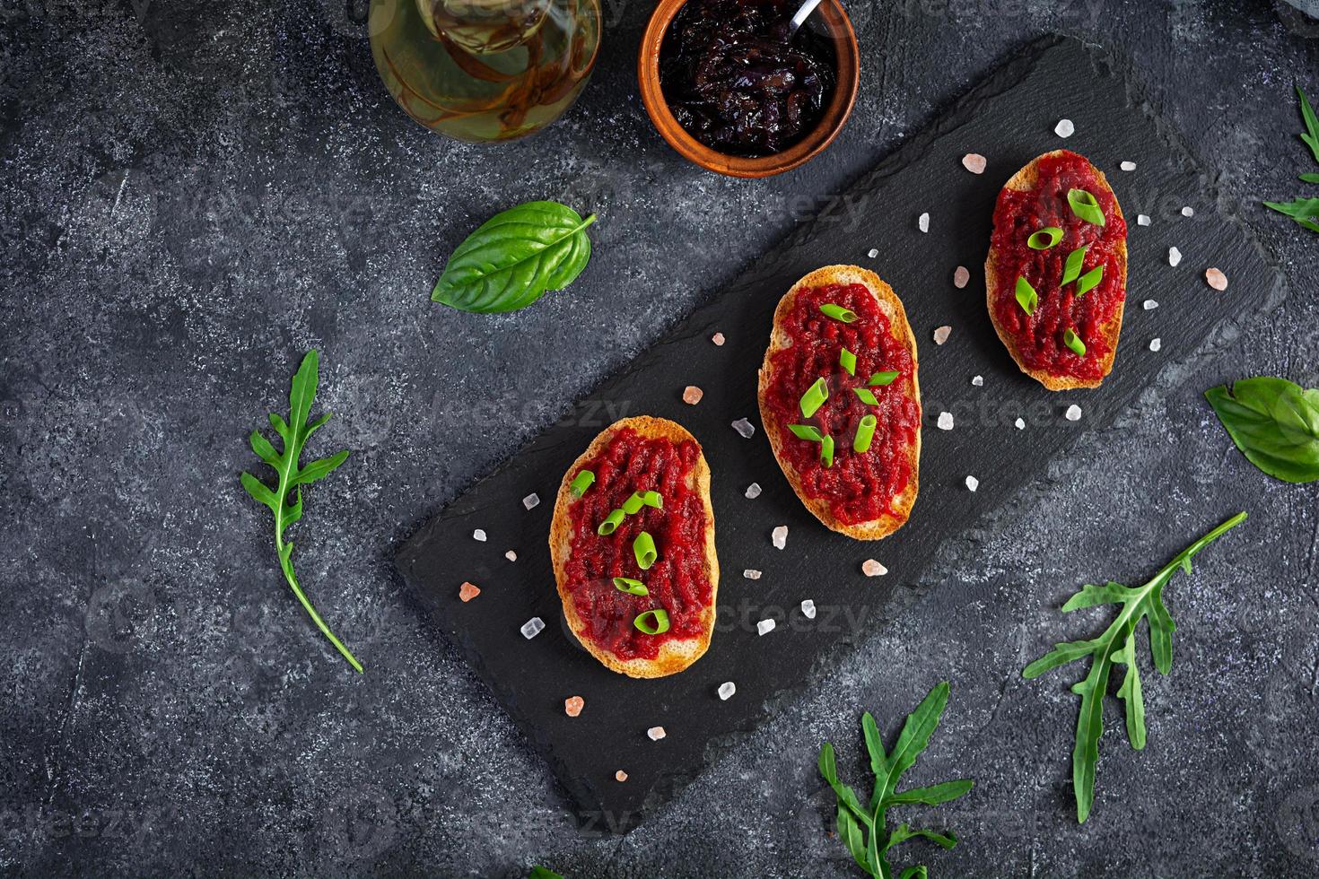 Bruschetta with grated beetroot, herbs and caramelized onion. Top view photo