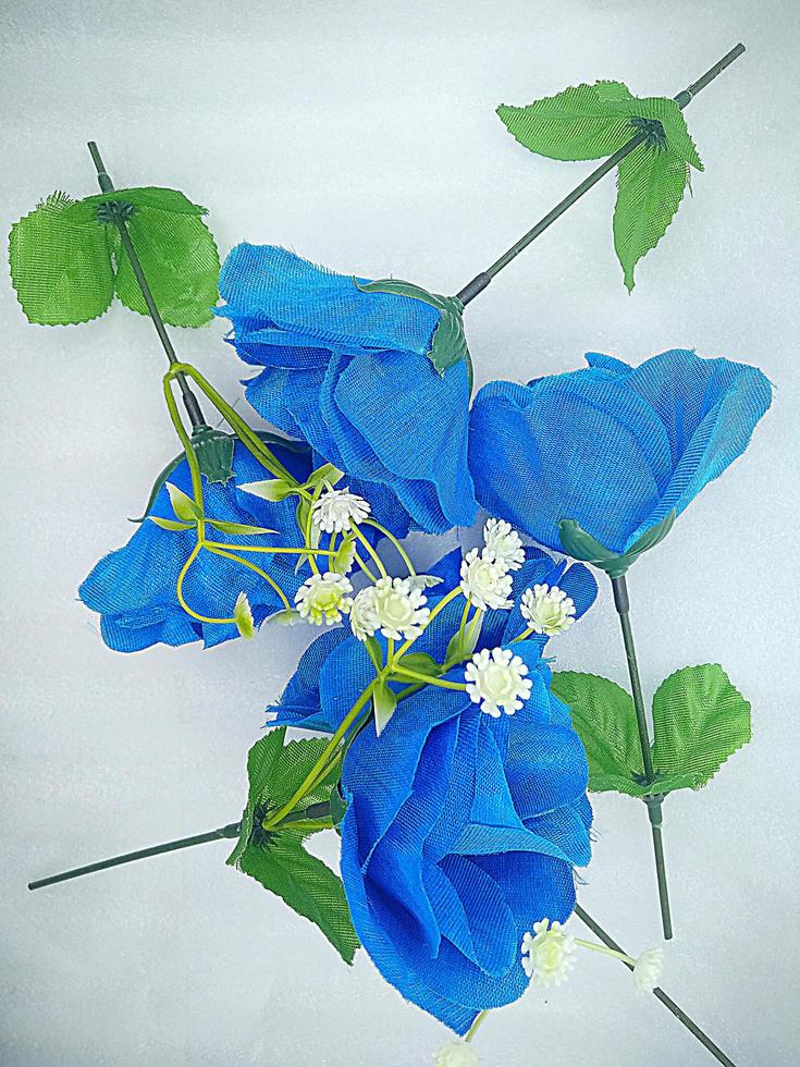 A blue ornamental flower whose petals are made of cloth and the stem is made of plastic on an isolated white background photo