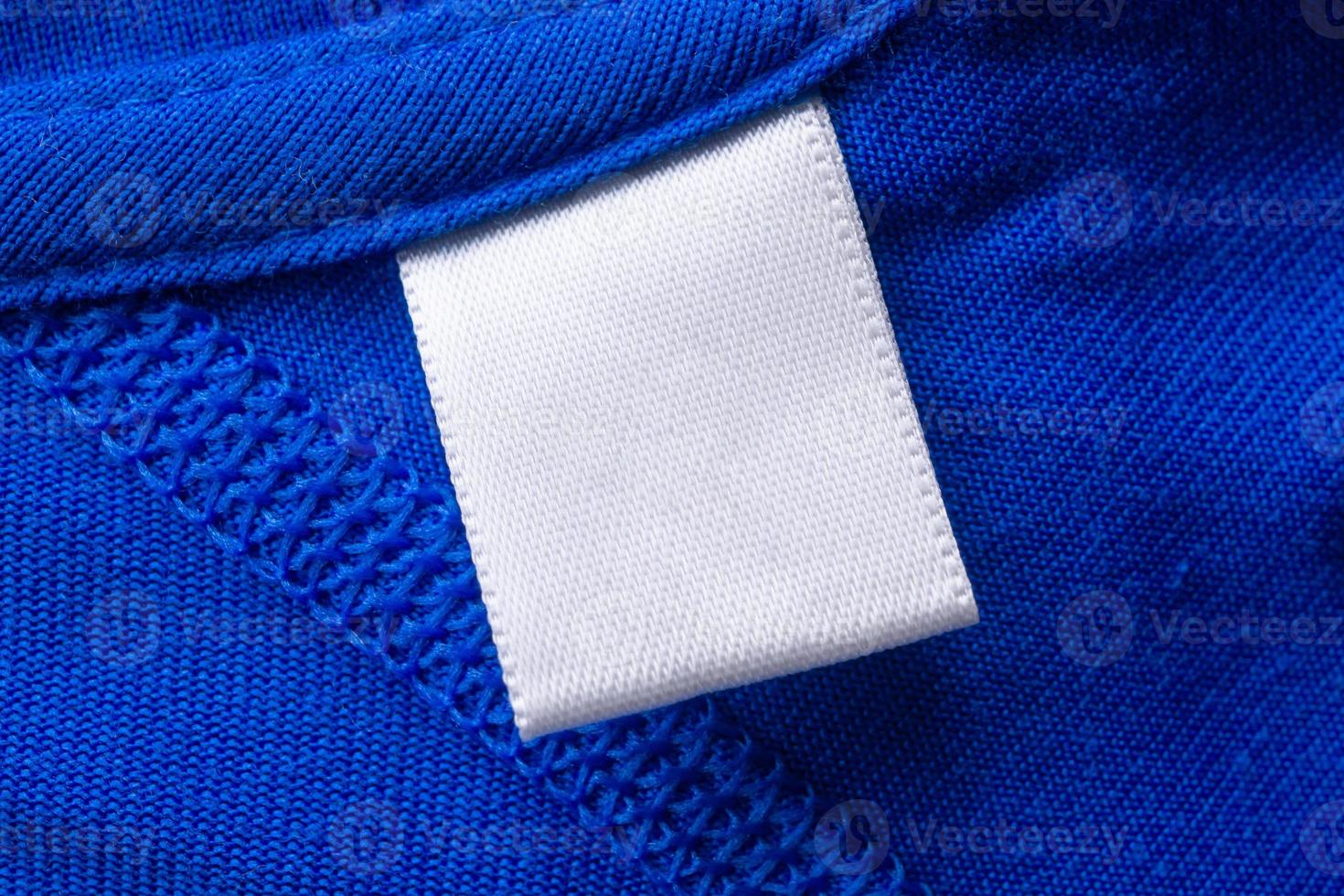 Blank white laundry care clothes label on blue fabric texture background photo