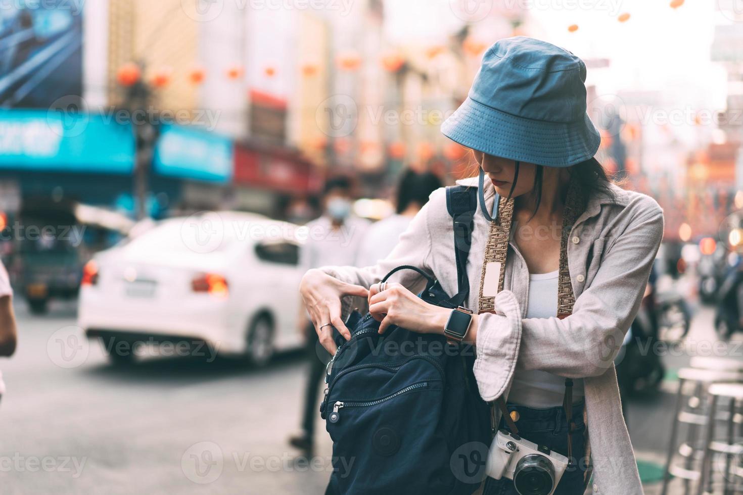 Young adult asian woman traveller opening backpack city street background. photo