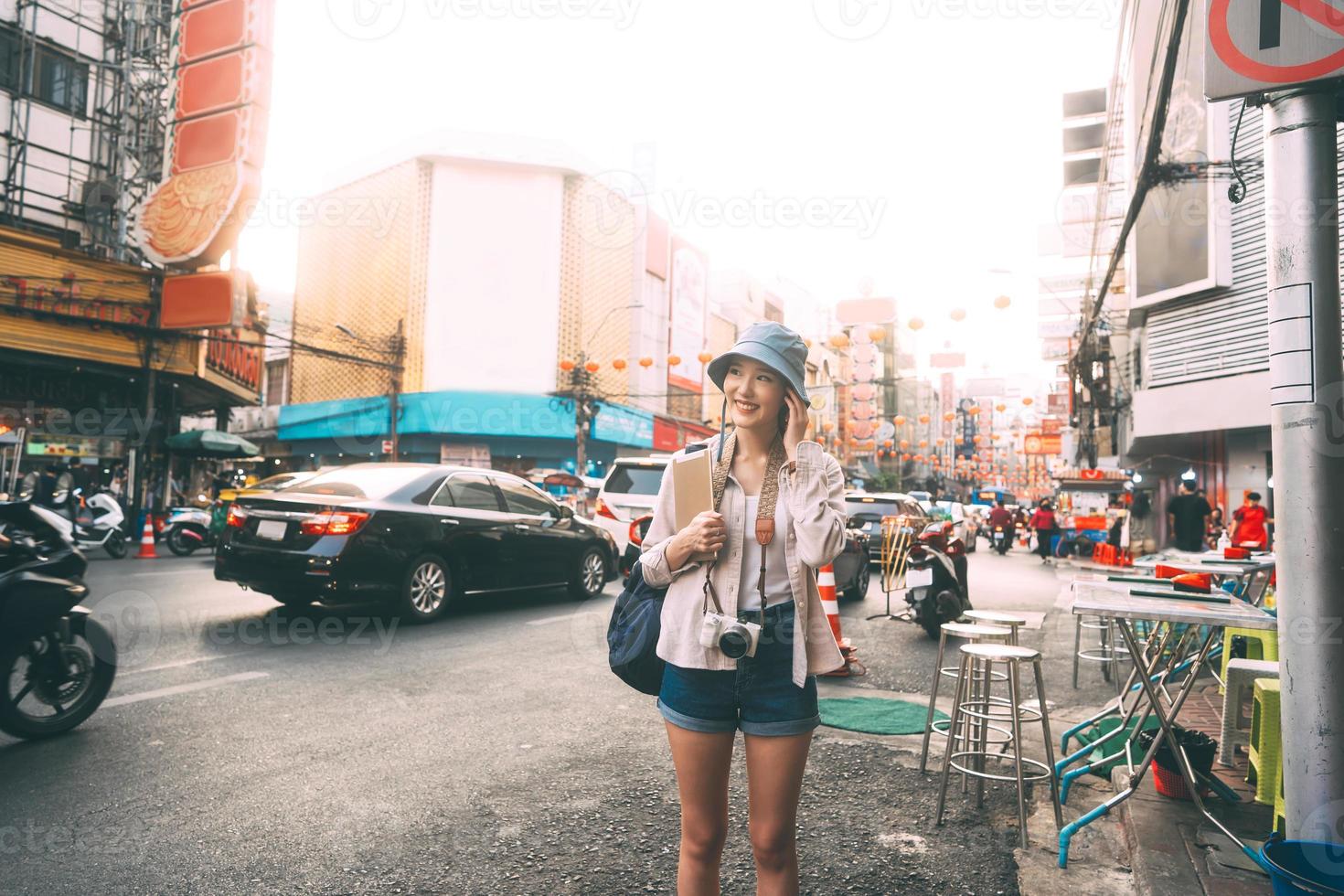 Caminando a una joven adulta asiática que viaja sola viajando con una tableta digital en la ciudad el día. foto
