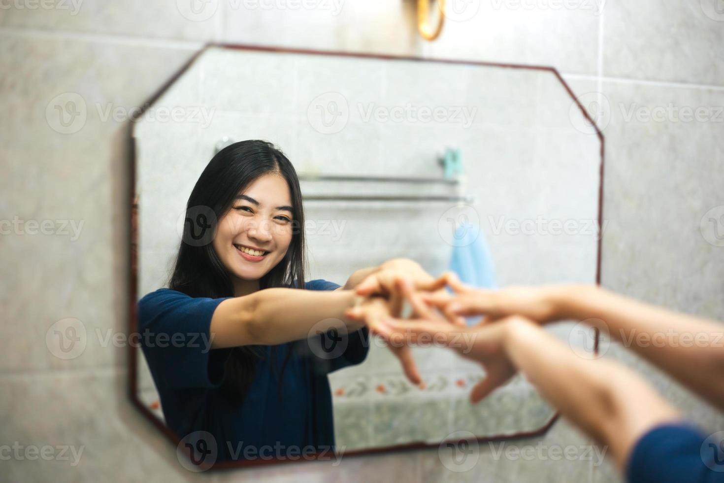 Young adult smile asian woman practice self talk conversation in the morning in bathroom at home. photo