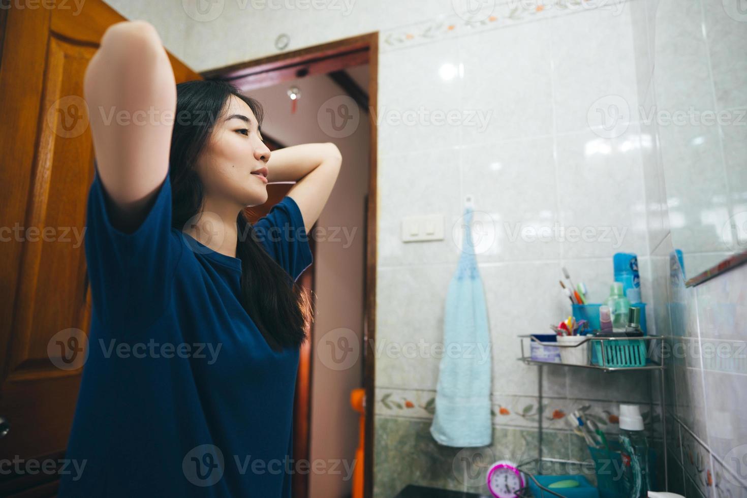 Young adult asian woman practice self and checking by mirror in bathroom at home. photo