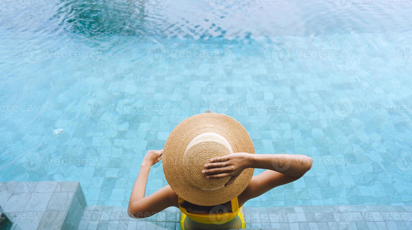 Rear and top view of asian woman relax at pool resort  travel on summer holiday. photo