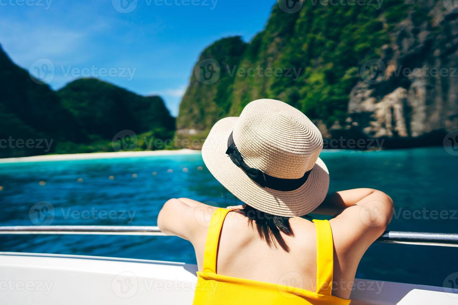 vista trasera de una mujer viajera adulta relájese en el velero con isla de verano y mar foto