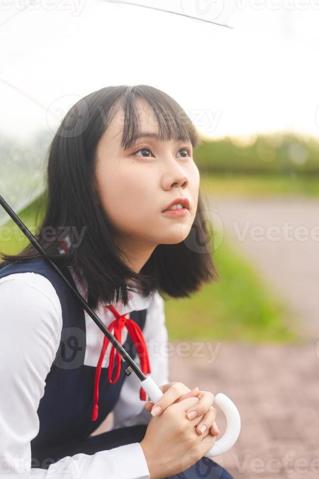 retrato de mujer joven cosplay cabello corto usar uniforme de escuela secundaria de estudiante japonés con paraguas foto