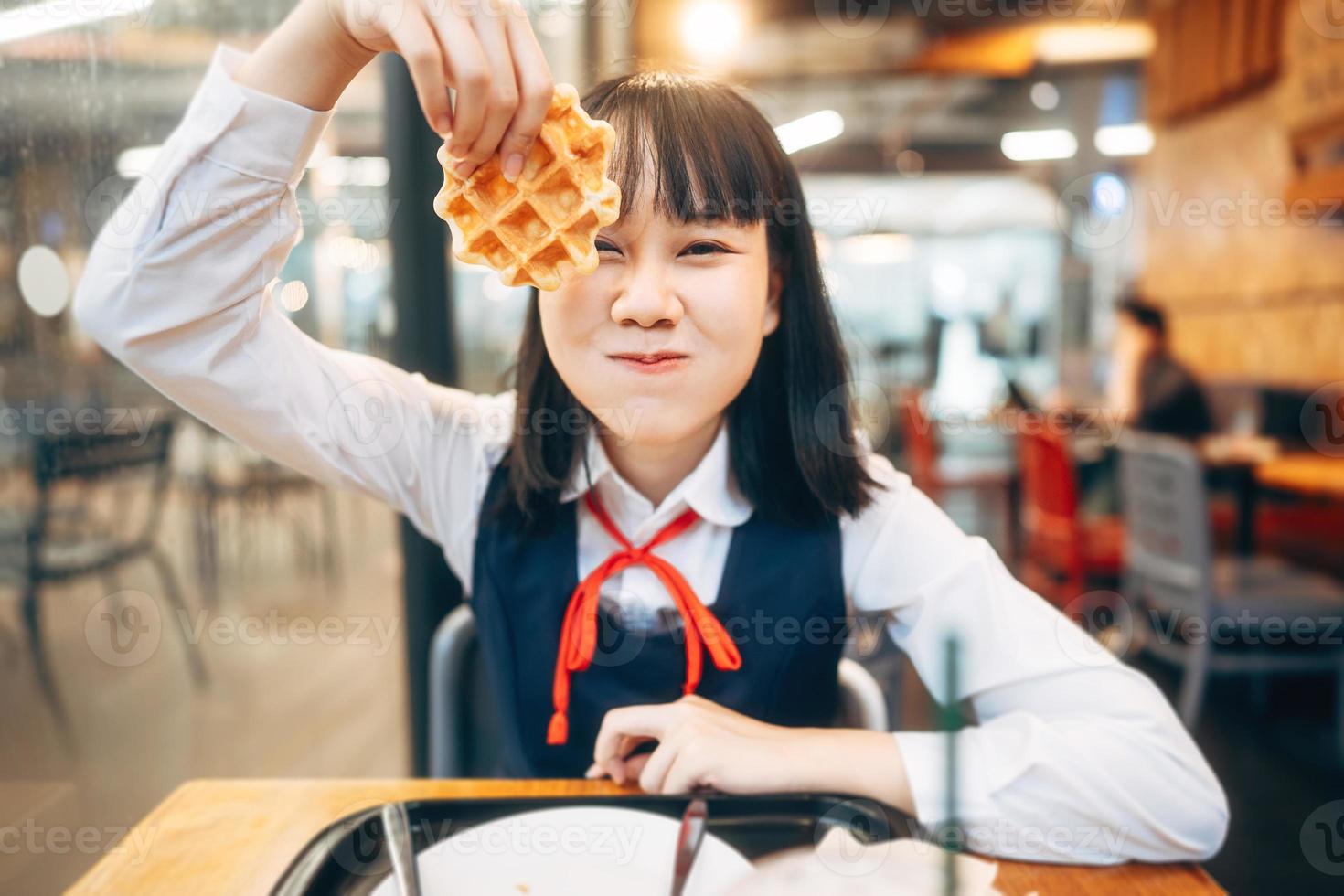 Happy young asian woman in japanese uniform student at cafe with waffle photo