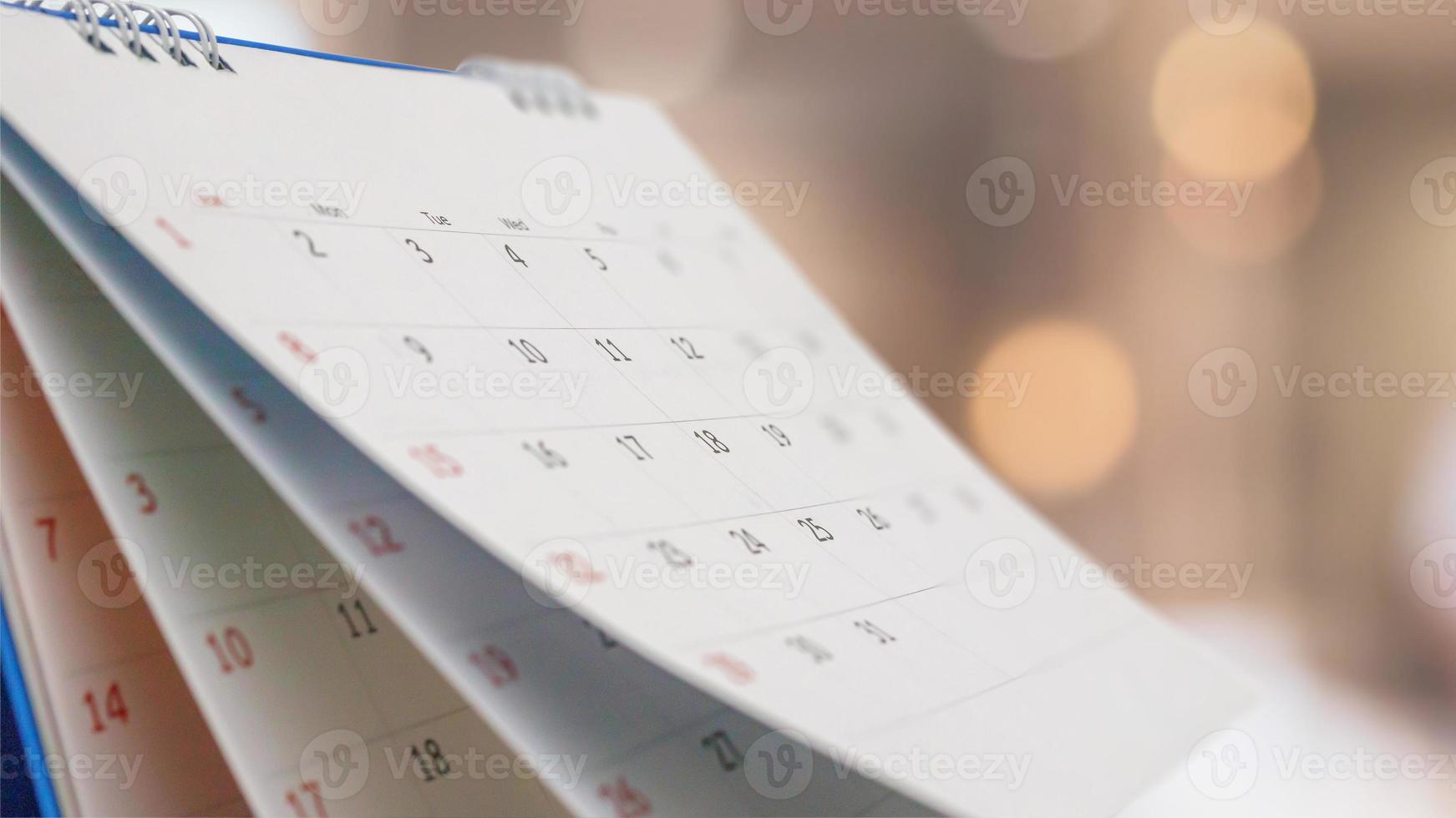 Close up white paper desk calendar with blurred bokeh background appointment and business meeting concept photo
