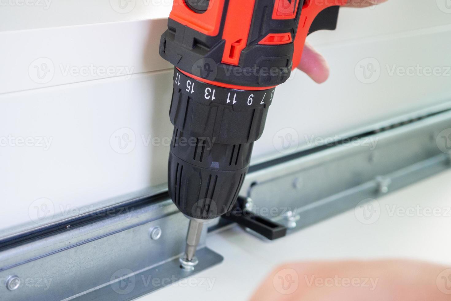 man assembling white table furniture at home using cordless screwdriver photo