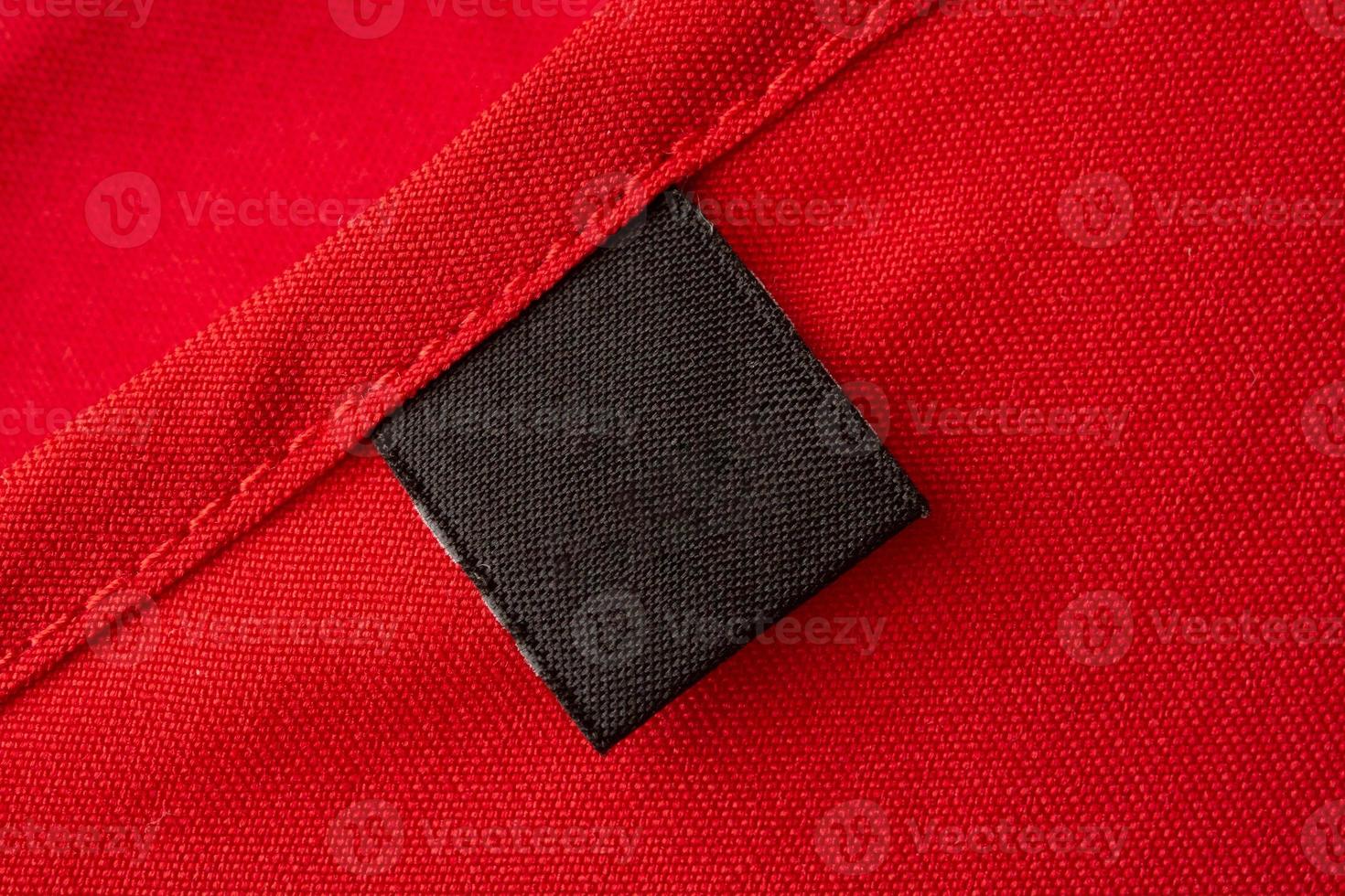 Blank black laundry care clothes label on red fabric texture background photo