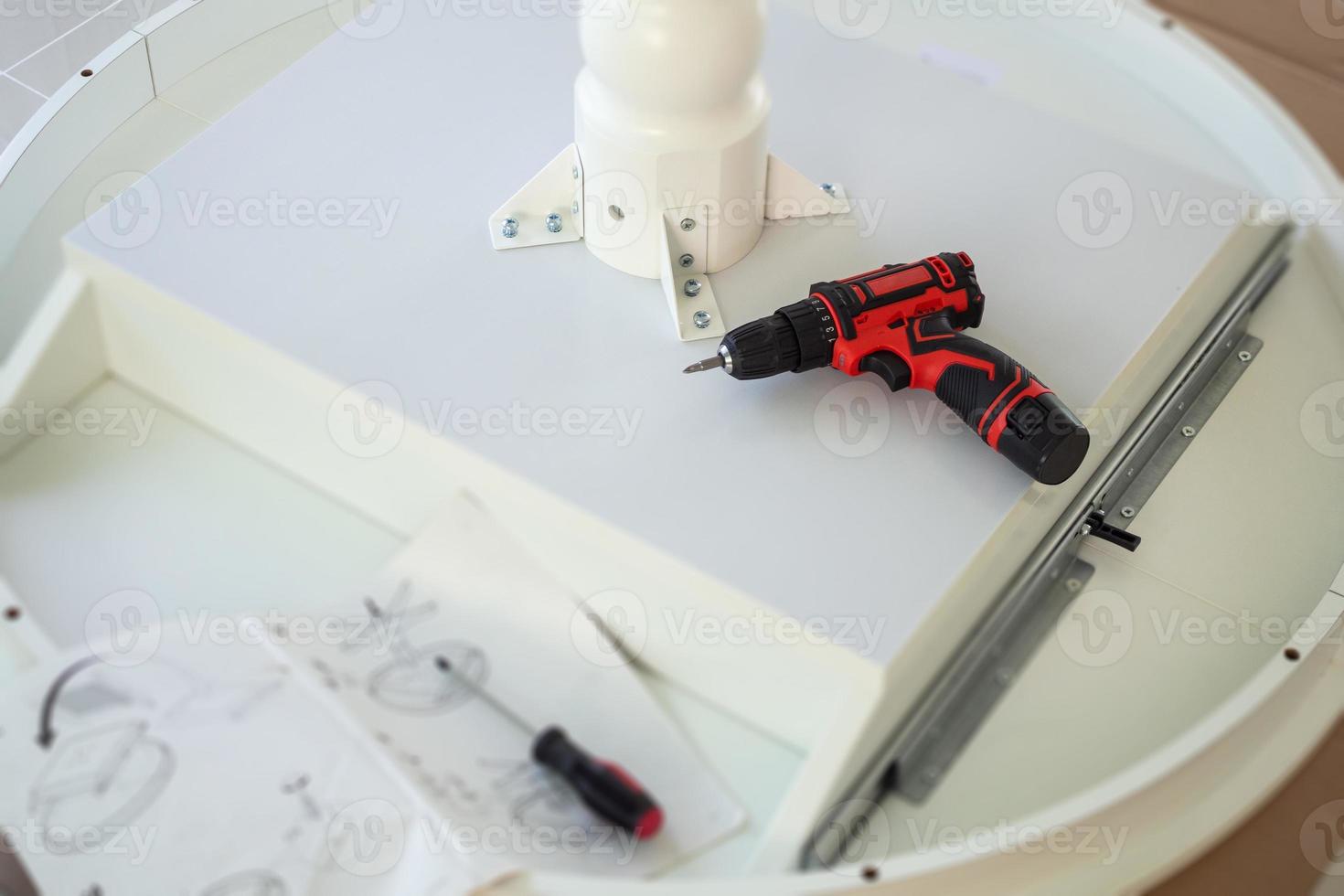 Cordless screwdriver on wood table assembly furniture concept photo