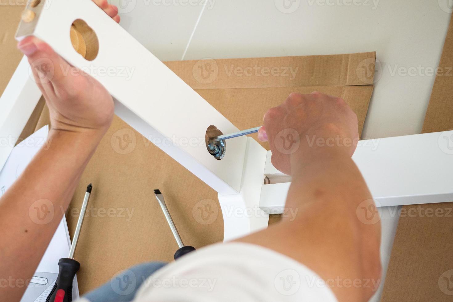 hombre montando muebles de silla blanca en casa foto