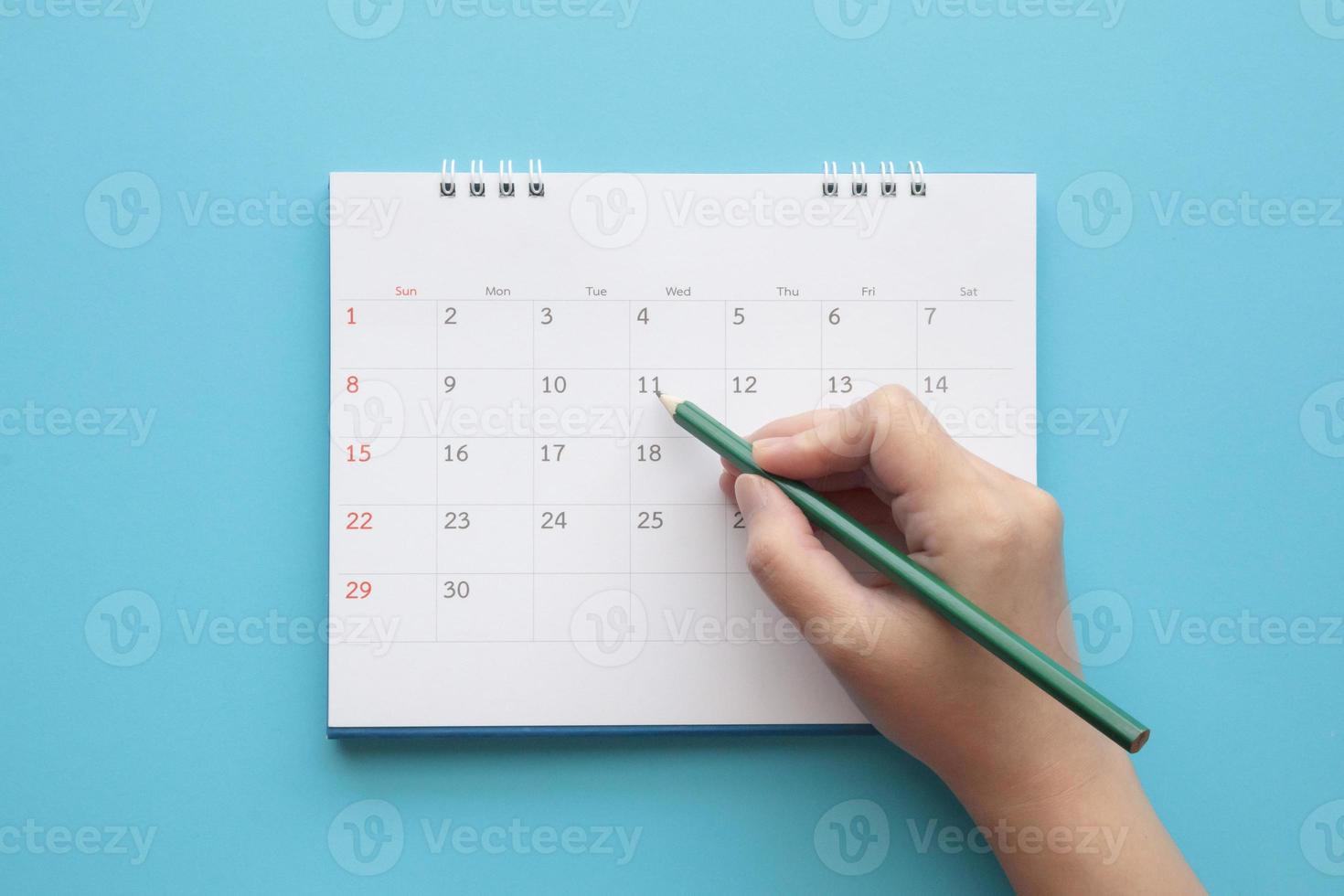 Hand with pencil mark on calendar date photo