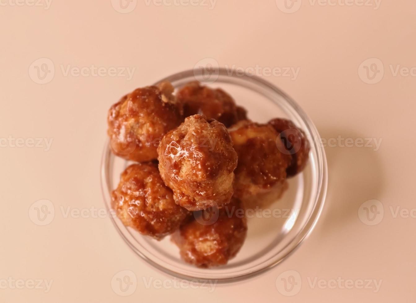 Selective focus of many candied macadamia nuts spinning in a small bowl. photo