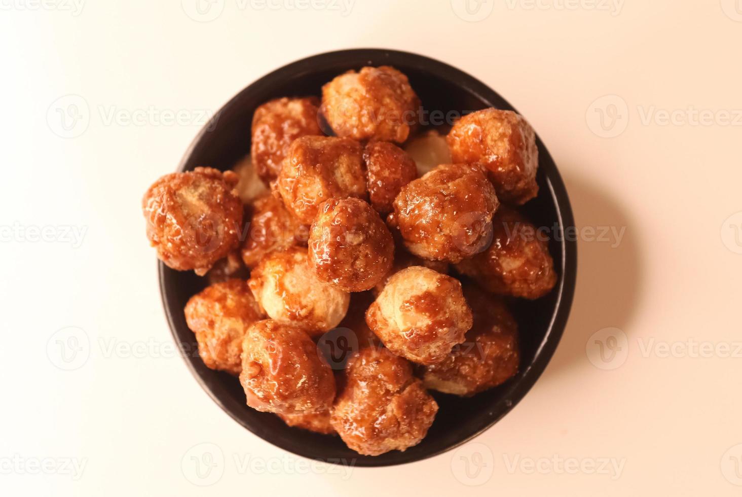 Selective focus of many candied macadamia nuts spinning in a small bowl. photo
