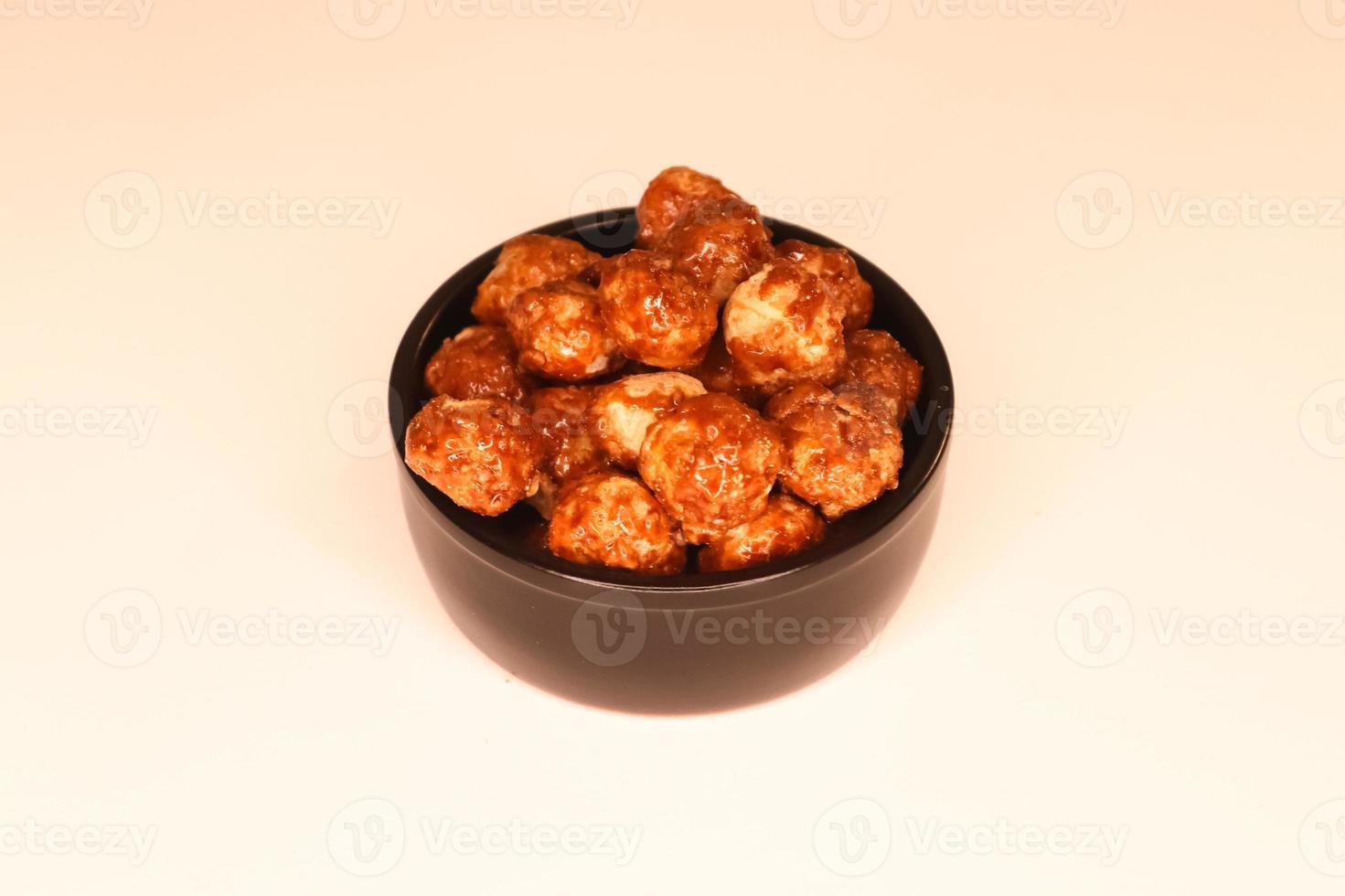 Selective focus of many candied macadamia nuts spinning in a small bowl. photo