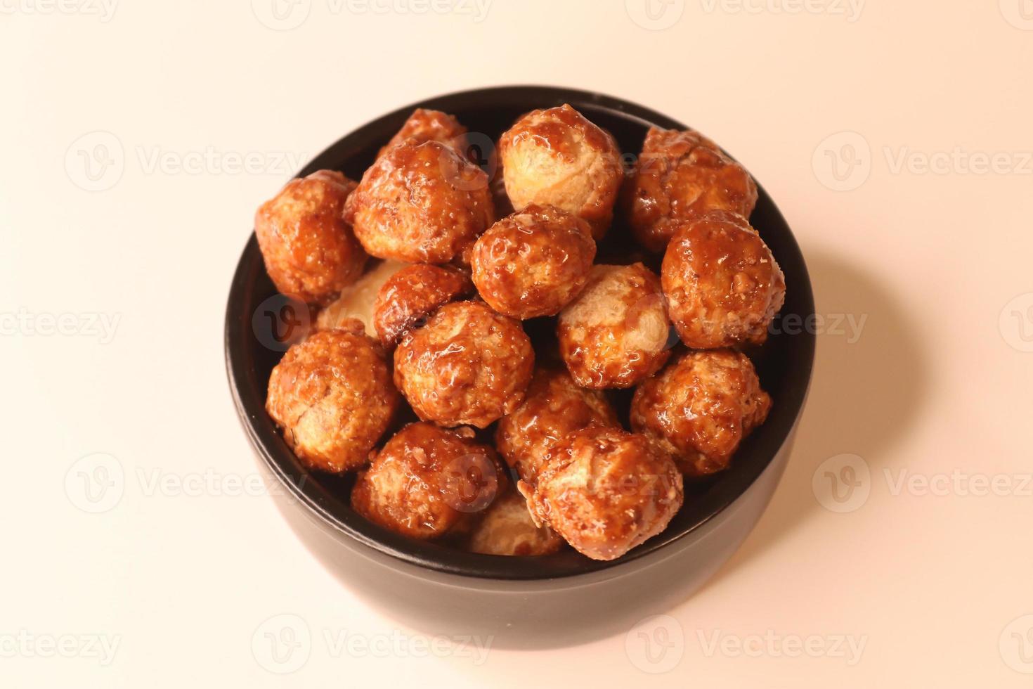 Selective focus of many candied macadamia nuts spinning in a small bowl. photo