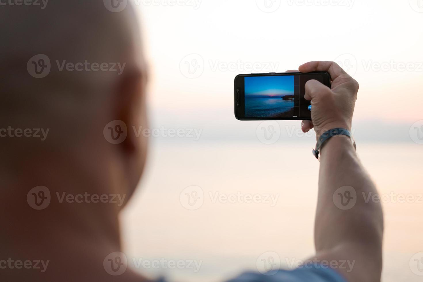 hombre tomando una foto increíble puesta de sol usando la cámara del teléfono inteligente, mano turística sosteniendo