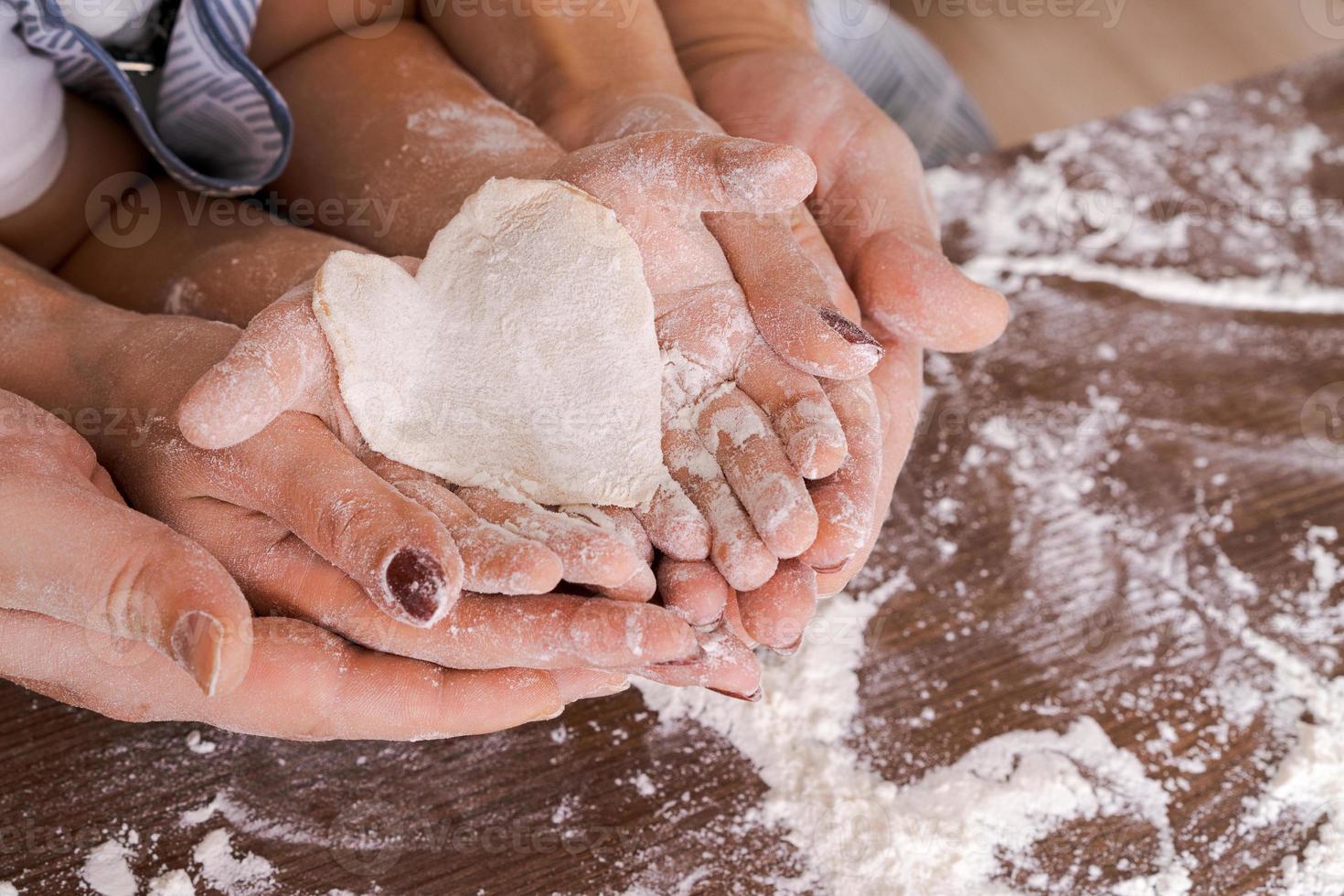 familia en la cocina, la palma de cerca desde arriba yace una masa en forma de corazón foto