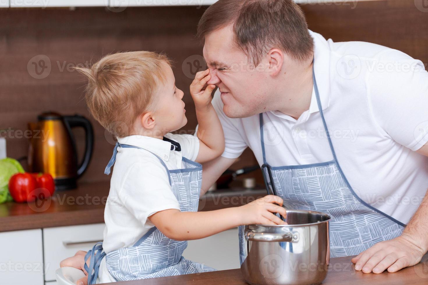 Boy and his father are preparing soup together in kitchen at home. Having fun photo
