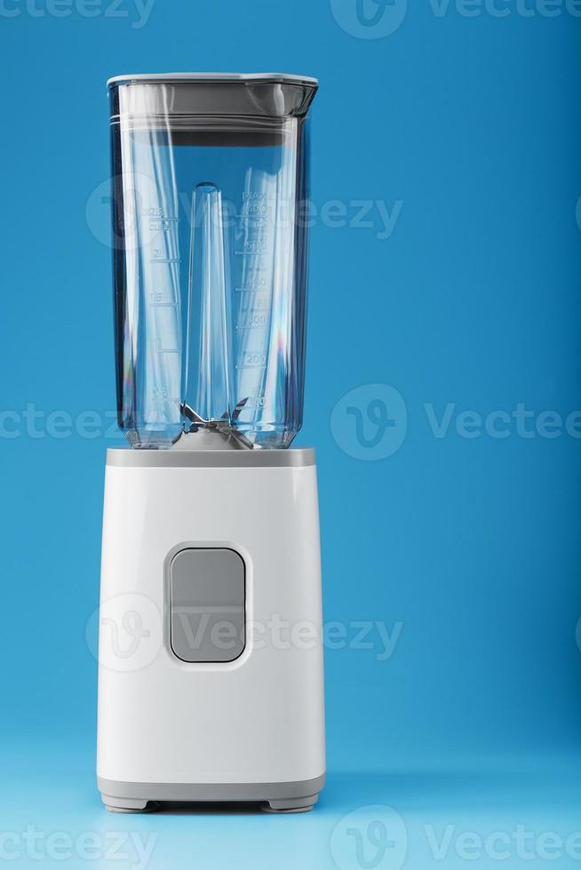 licuadora eléctrica con una taza vacía sobre un fondo azul. foto