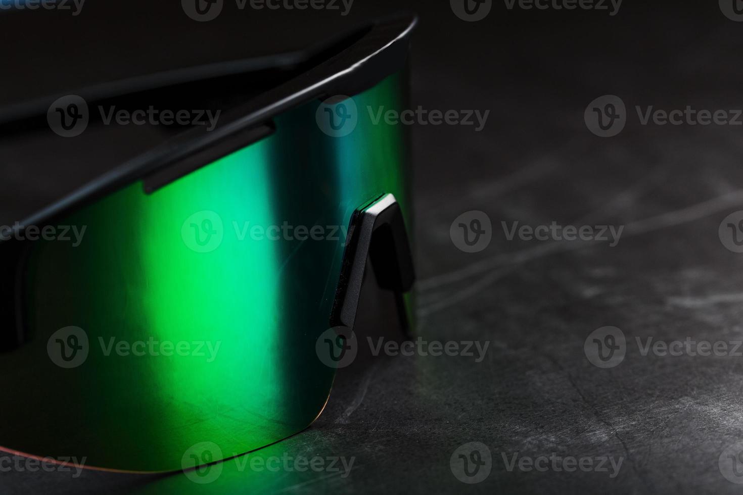 Green sports glasses with a mirror lens on a dark background photo