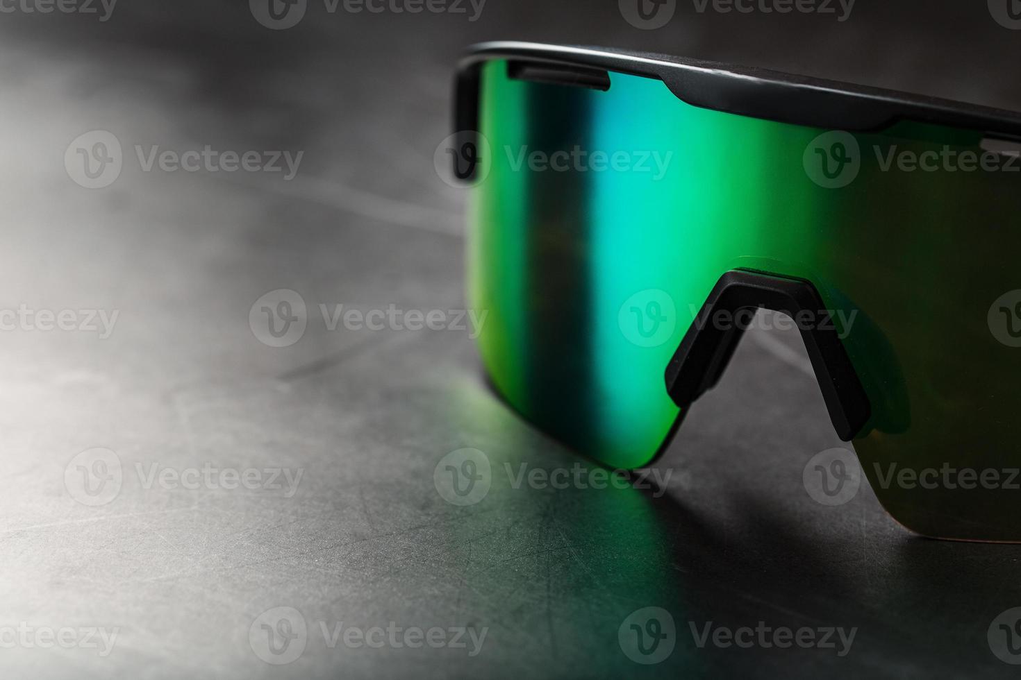 Green sports glasses with a mirror lens on a dark background photo