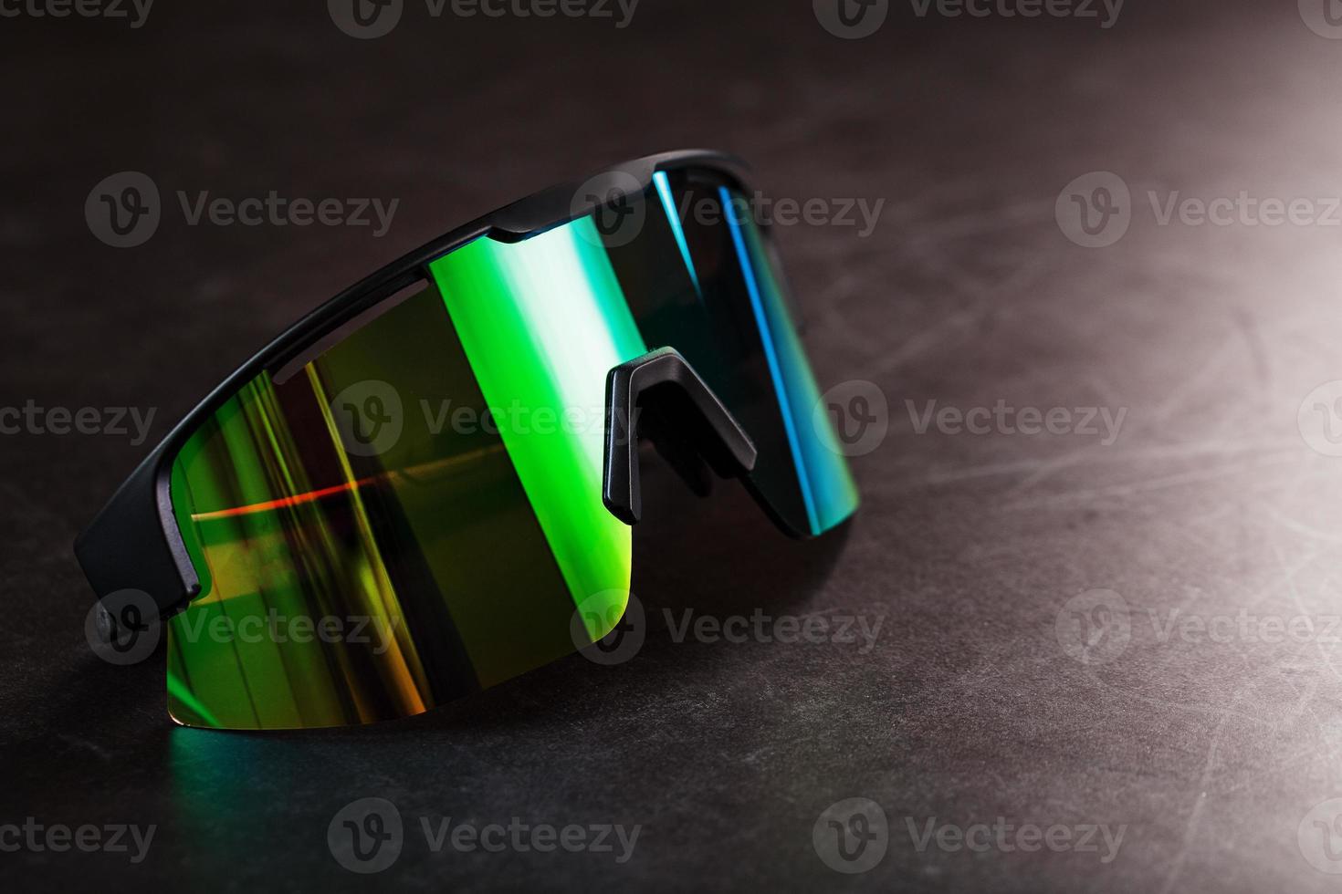 Green sports glasses with a mirror lens on a dark background photo