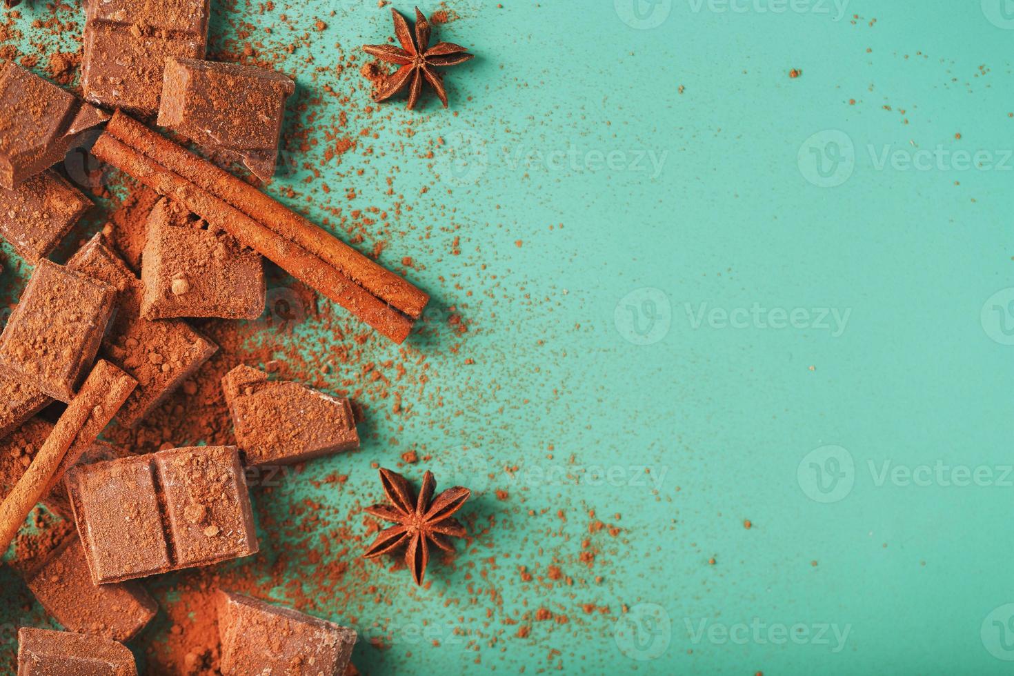 Milk chocolate with spices and cocoa on a green background. photo